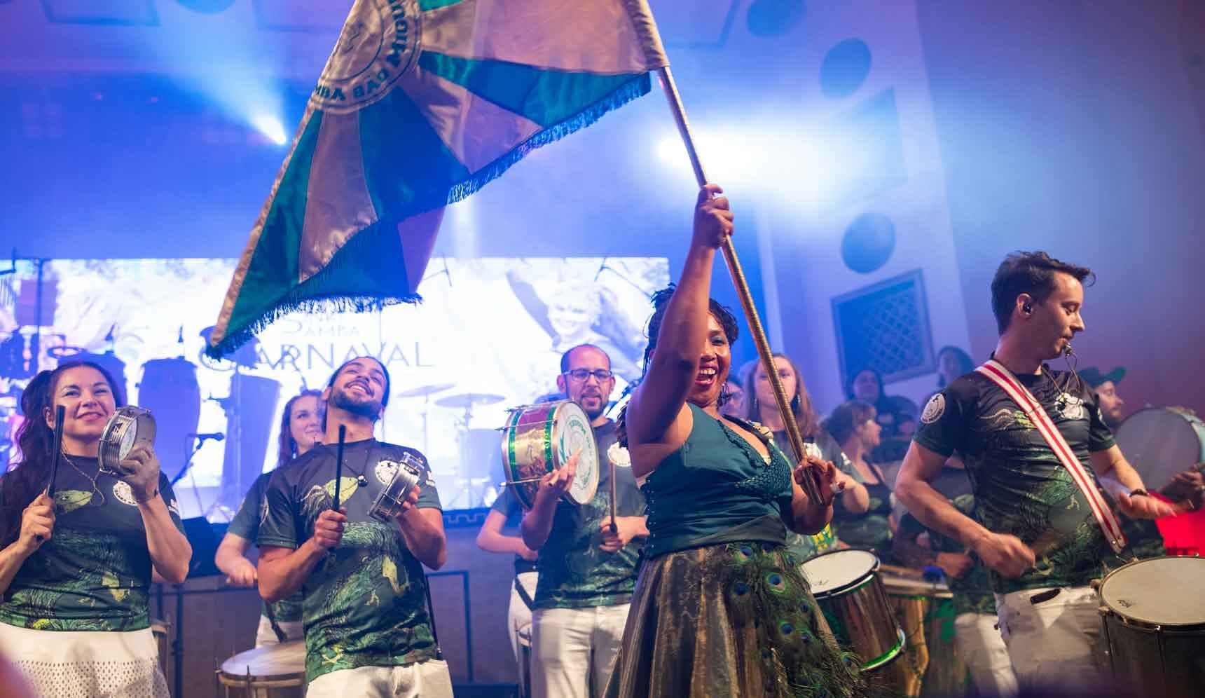 Group on stage with porta-bandeira and flag in front